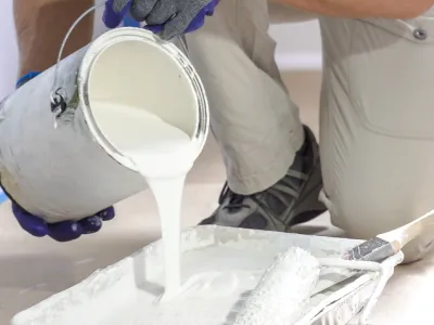 Pot de peinture blanche versé dans un bac à peinture.